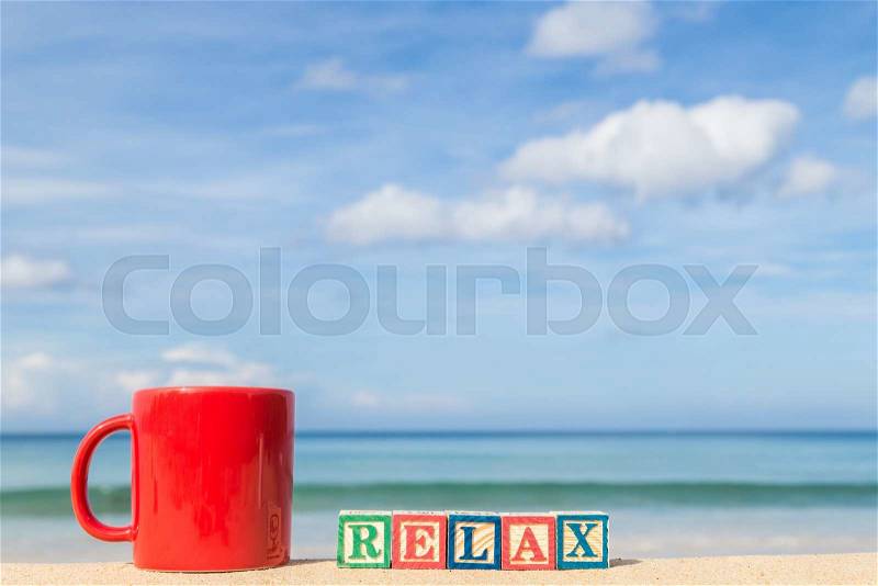 Word RELAX in colorful alphabet blocks and coffee cup on tropical beach, Phuket Thailand, stock photo