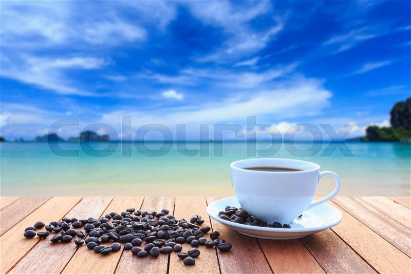 Close up white coffee cup and coffee beans on wood table and view of sunset or sunrise background, stock photo