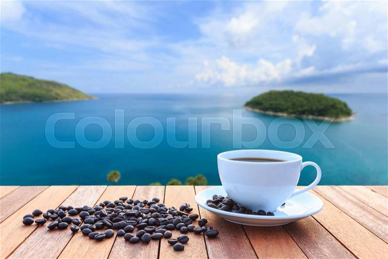 Close up white coffee cup and coffee beans on wood table and view of sunset or sunrise background, stock photo