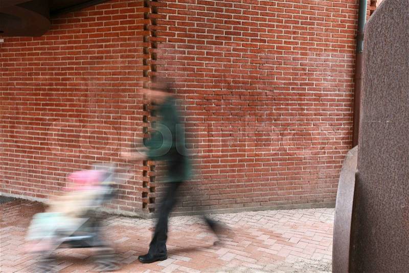 People passing by a brick wall, stock photo