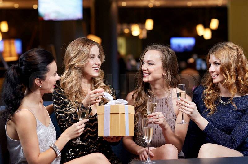 Celebration, friends, bachelorette party, birthday and holidays concept - happy women with champagne glasses and gift box at night club, stock photo
