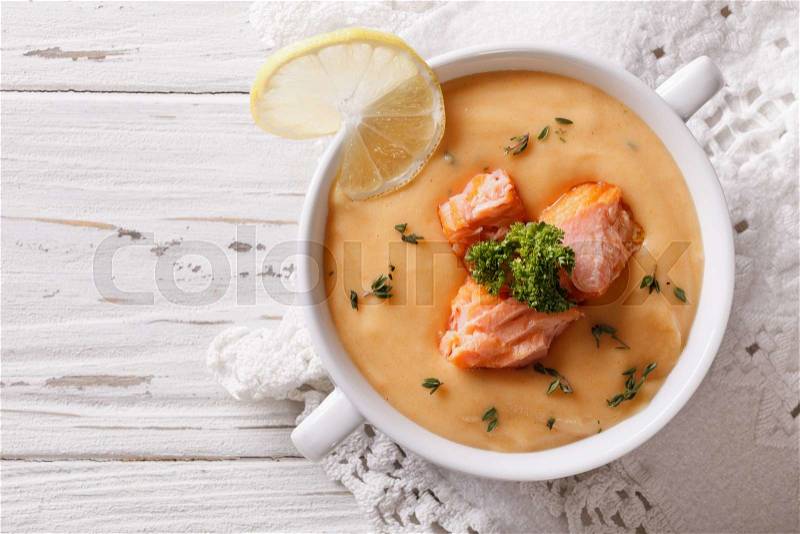 Salmon cream soup with lemon in a white bowl on the table. horizontal top view , stock photo