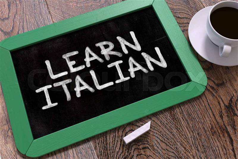 Learn Italian - Green Chalkboard with Hand Drawn Text and White Cup of Coffee on Wooden Table. Top View, stock photo