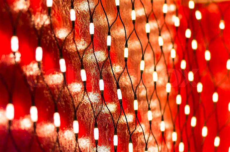 Christmas lights on dark red wall background, stock photo