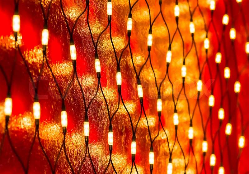 Christmas lights on dark red wall background, stock photo