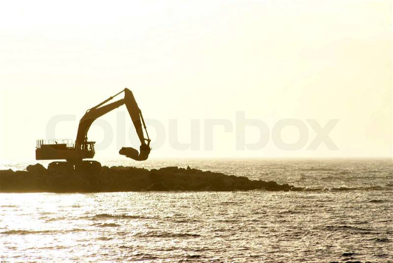 Excavator working at coastal protection, stock photo