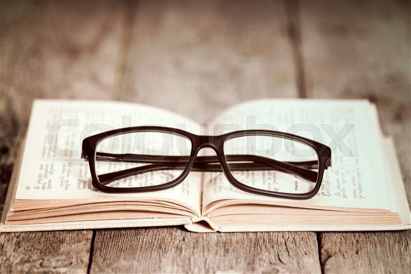 Closeup of reading glasses on the old book, stock photo