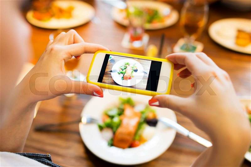 People, leisure, technology and internet addiction concept - close up of woman with smartphone photographing food at restaurant, stock photo