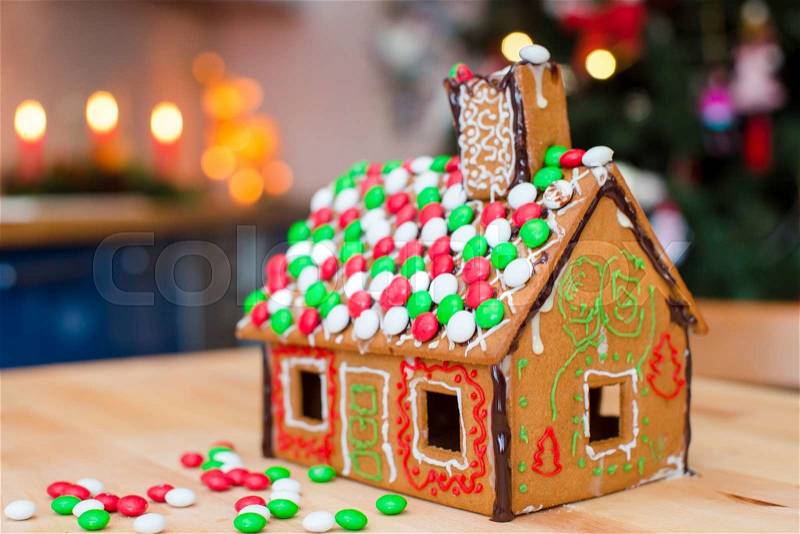 Cute gingerbread man in front of his candy ginger house background the Christmas tree lights, stock photo