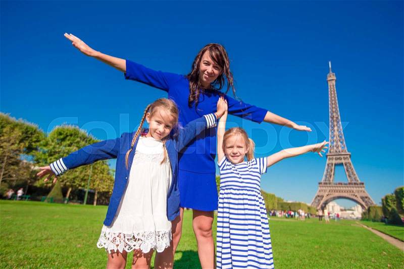 Happy family in Paris near Eiffel tower. French summer holidays, travel and people concept, stock photo