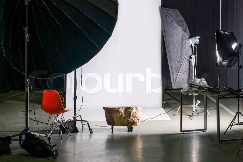 Empty photo studio with modern interior and lighting equipment. Preparation for studio shooting: empty chair and studio lighting, stock photo