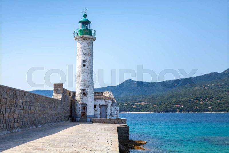 White stone lighthouse tower on the pier. Entrance to Propriano port, Corsica island, France, stock photo