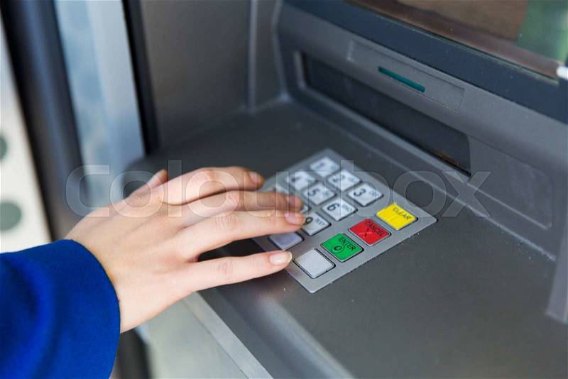 Finance, technology, money and people concept - close up of hand entering pin code at cash machine, stock photo