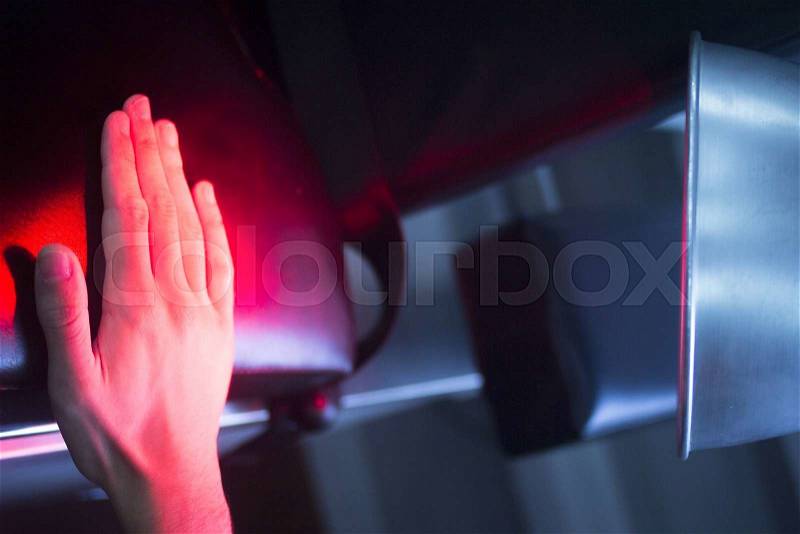 Patient hand in red physiotherapy heat treatment under hot light, stock photo
