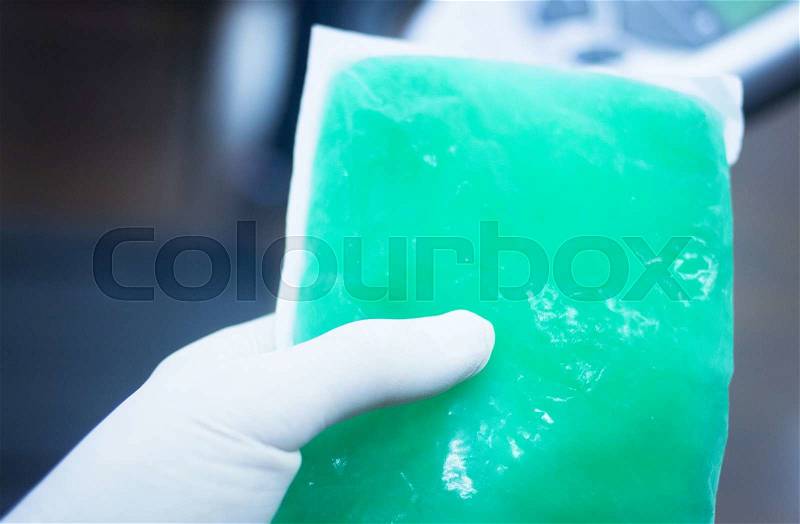 Green physiotherapy cold muscle injury gel pack forzen in freezer in sports injury medical clinic for physical therapy and rehabilitation for orthopedics and traumatology in hand of physiotherapist, stock photo