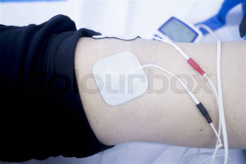 Patient leg and knee in electro physiotherapy electrical impulse stimulation rehabiliation treatment from injury in hospital clinic with electrical stimulus attached with plaster. , stock photo
