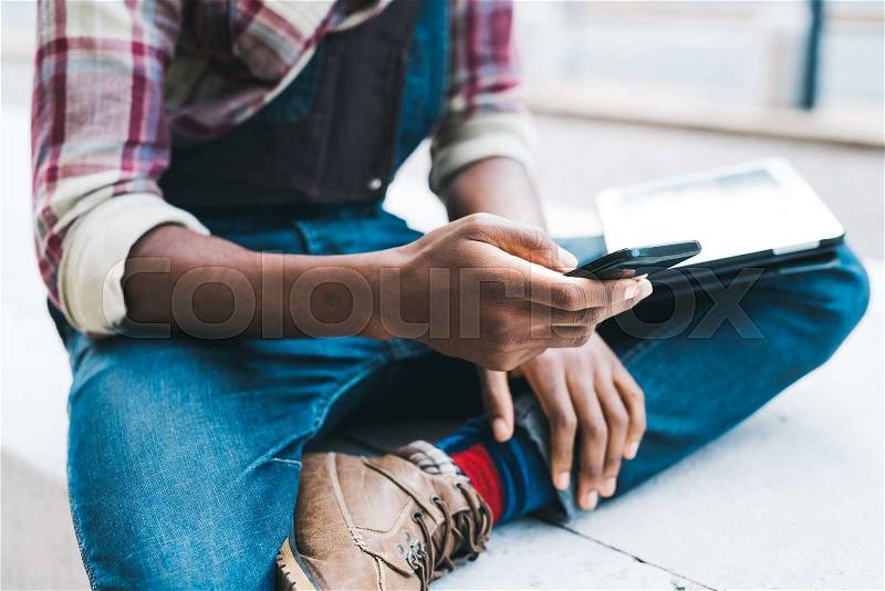 Close up on the hand of a young handsome afro black man using a smartphone, tapping the screen - technology, social network, communication concept, stock photo