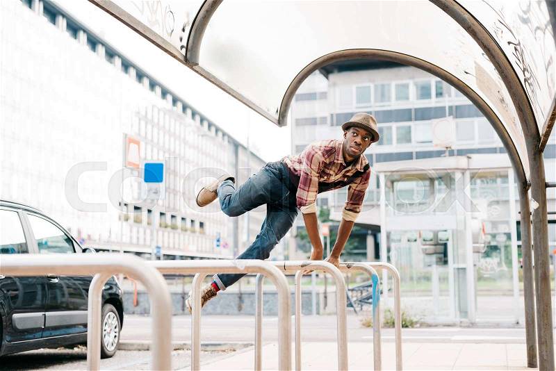 Young handsome afro black man jumping leaning his hand on a handrail, looking straight - sportive, athletic concept, stock photo