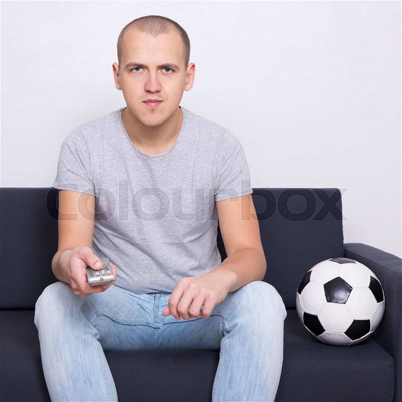 Young handsome man watching soccer on tv at home, stock photo