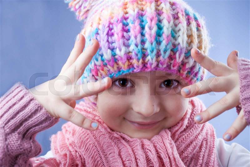 Little girl in knitted winter hat, scarf and mitten, stock photo