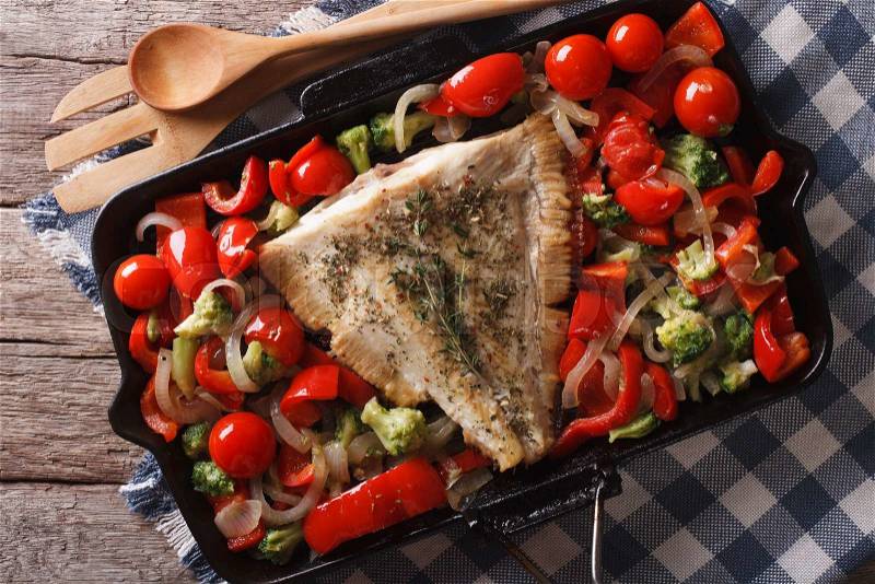Flounder with vegetables close-up on a frying pan on the table. Horizontal top view , stock photo