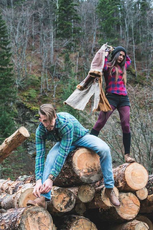 Young woman and men on wood logs in the forest, stock photo