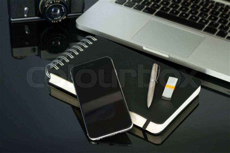 Office black glass desk table with phone, laptop and supplies
