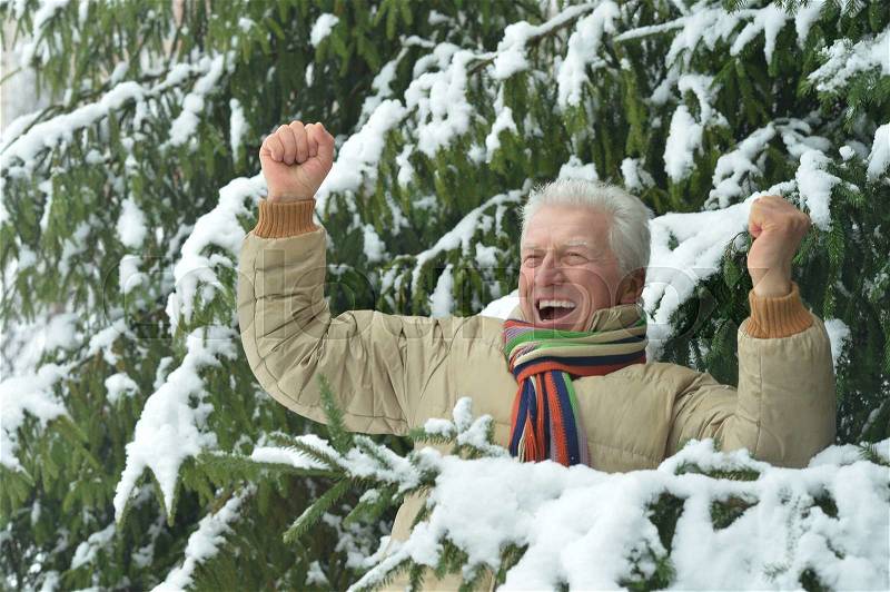 Senior man standing outdoor in winter with hands up, stock photo