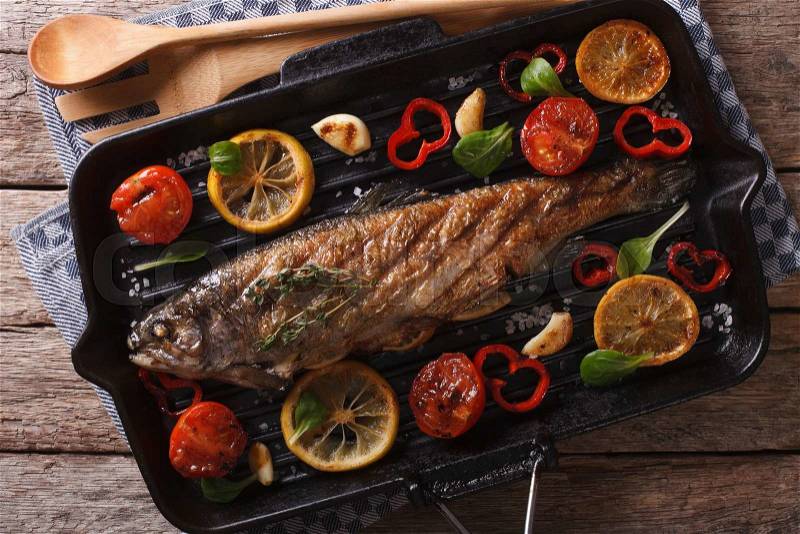 Trout with vegetables on a grill pan close-up on the table. horizontal view from above , stock photo