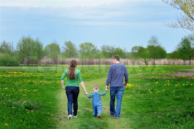 Happy young family walking down the road outside in green nature, stock photo