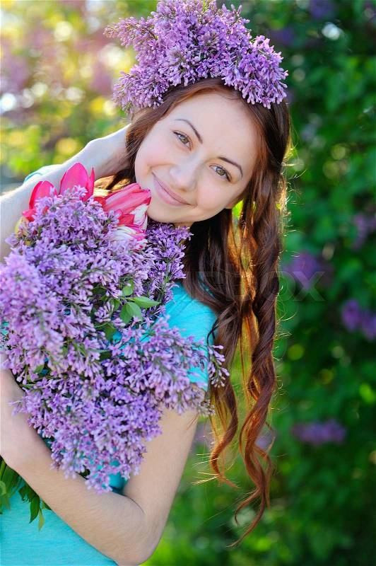 Beautiful girl with a bouquet of lilac in the hands walking in the spring park, stock photo
