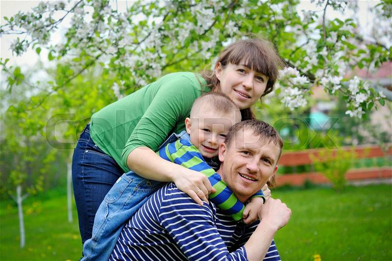 Young family walks in the spring garden with a child, stock photo
