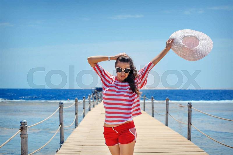 Young woman full of energy on a pontoon in front of the sea on a sunny day, stock photo