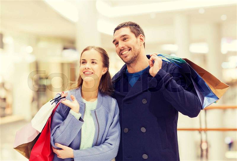 Sale, consumerism and people concept - happy young couple with shopping bags walking in mall, stock photo