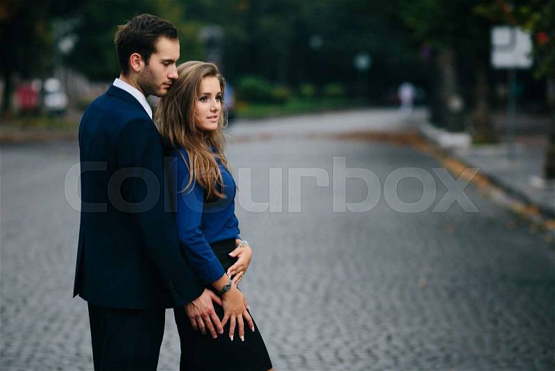 Guy hugging his girlfriend from behind in the city, stock photo