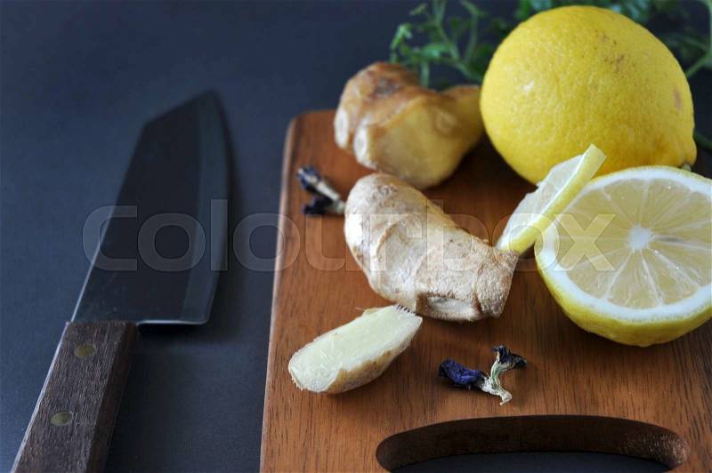 Ginger and lemon on wooden cutting board with knife, stock photo