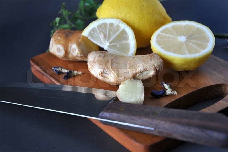 Knife on wooden cutting board with ginger and lemon, stock photo