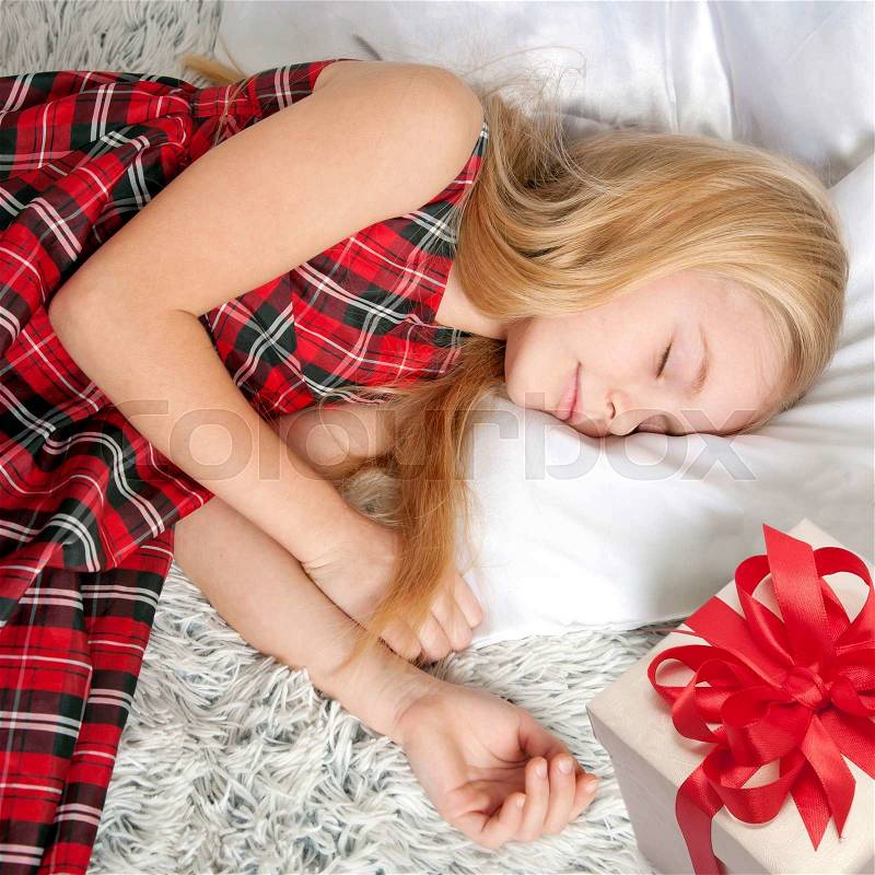 Adorable little girl sleeping. Somebody put a gift by her side. Dreams come true!, stock photo