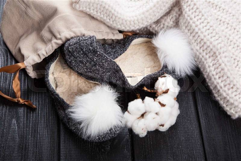 Cozy woolen home slippers on dark wood, stock photo