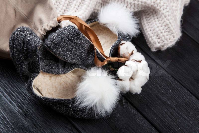 Cozy woolen home slippers on dark wood, stock photo
