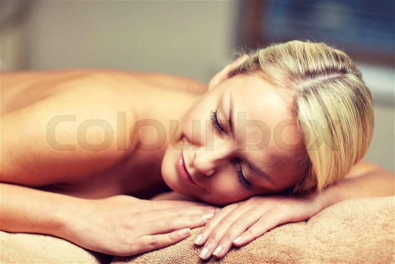 People, beauty, spa, healthy lifestyle and relaxation concept - close up of beautiful young woman lying on massage table in spa, stock photo
