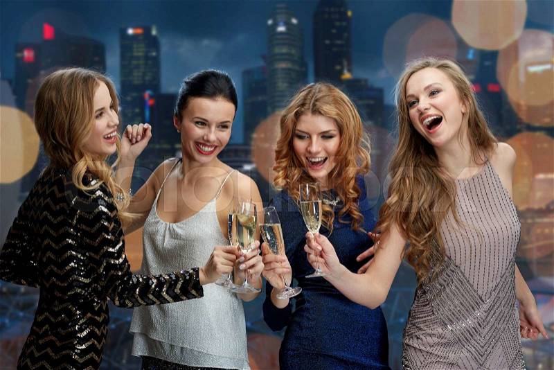 Celebration, friends, bachelorette party, nightlife and holidays concept - happy women clinking champagne glasses and dancing over night city lights background, stock photo