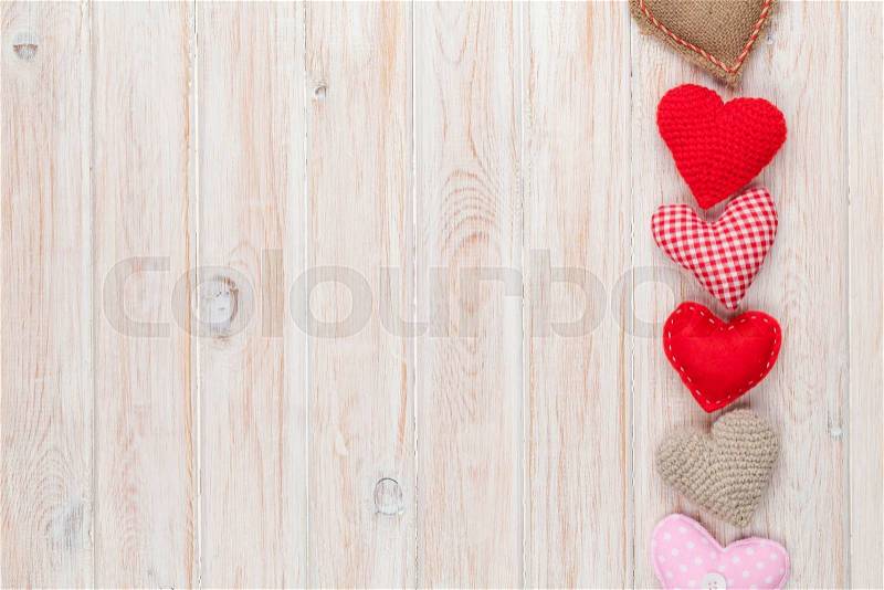 Valentines day background with toy hearts over white wooden table, stock photo