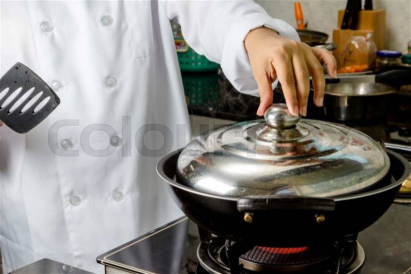Chefs opening the pan lid on hot stove, stock photo
