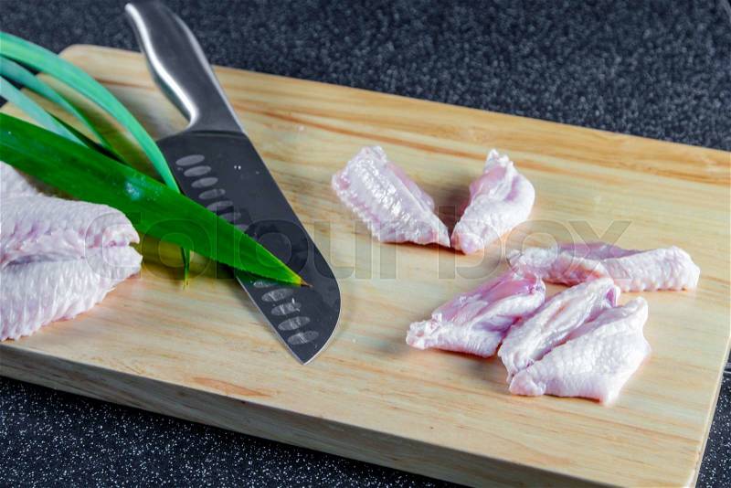 Raw chicken wing on chopping board, stock photo