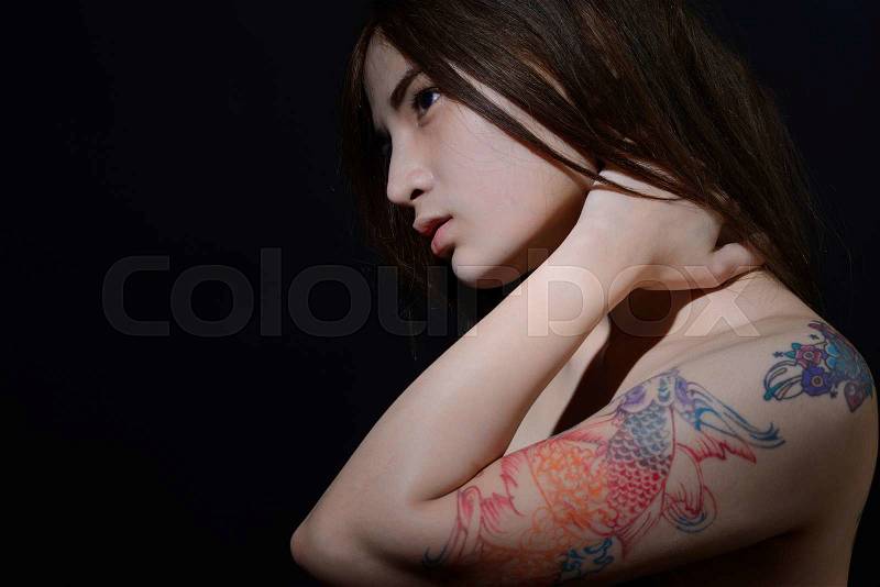 Beautiful asian woman with a tattoo on her arm and shoulder,dark background, stock photo