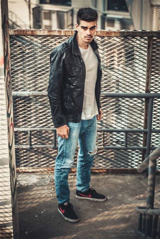 Young stylish man model posing in leather jacket. Agressive style, stock photo