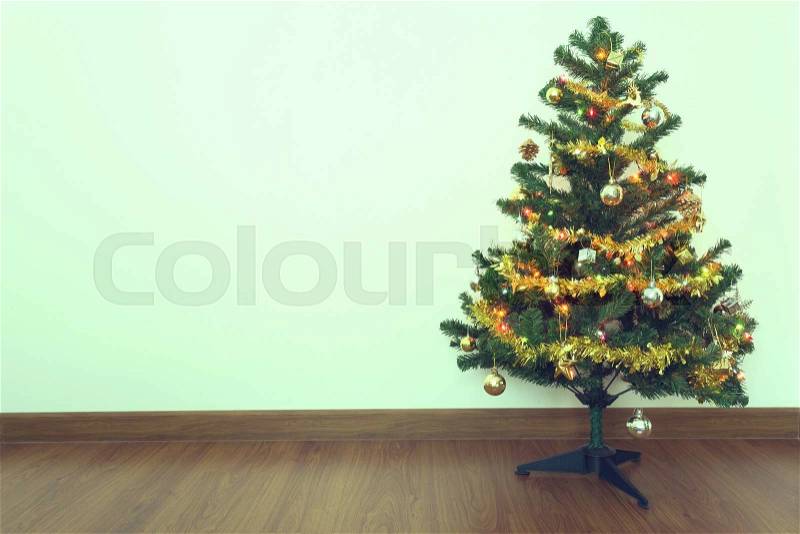 Christmas tree decoration in empty room with white wall and wooden laminate floor, stock photo