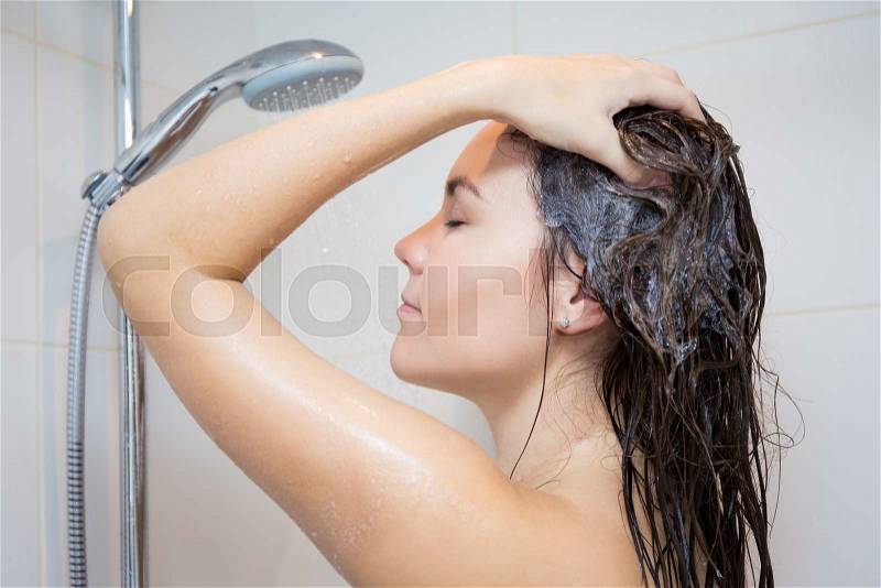 Body care concept - young beautiful woman washing her hair with shampoo in shower, stock photo