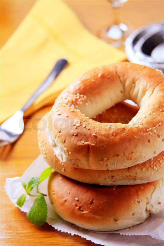Three sesame seed bagels on a paper bag, stock photo